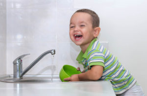 Little boy washing dishes