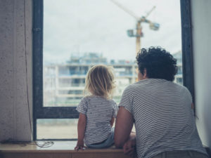 Parent and child looking out a window.