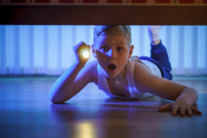 boy with a flashlight looking under bed