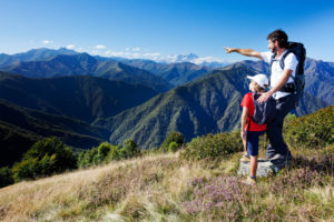 Man and young boy standing in a mountain meadow.