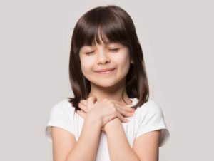 smiling girl with hands crossed at heart