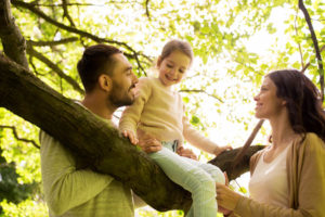 Mom, dad and daughter climbing a treell