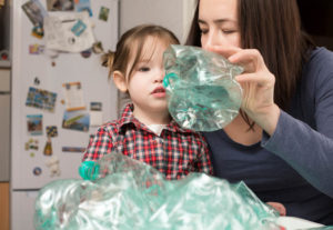 Little girl collecting plastic for recycling with her mother