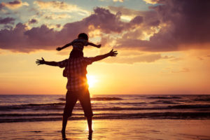 Father and son playing on the beach at the sunset time.