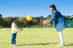 Parent and child playing ball in the park